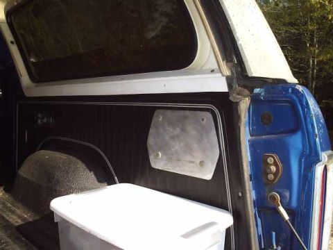1978 Ford Bronco - The rear interior of a blue and white SUV is shown, with a white storage bin in the cargo area.
