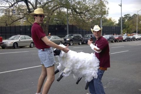 1988 Ford Bronco - Two men in cowboy hats and maroon shirts hold a fluffy white fake sheep with black legs and head.