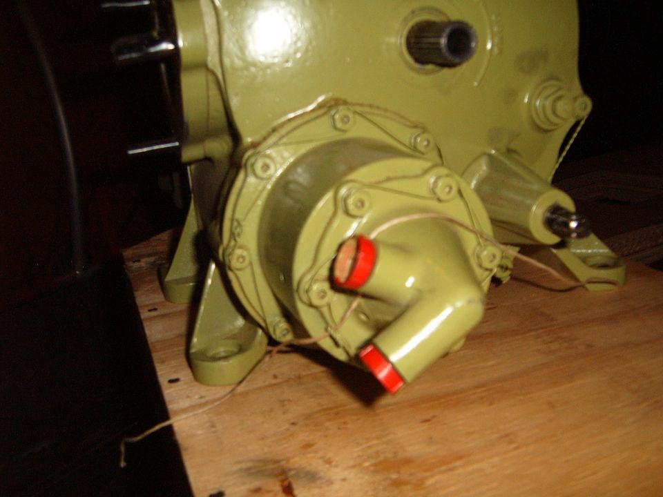 Green painted mechanical component with red capped fittings on a wooden surface