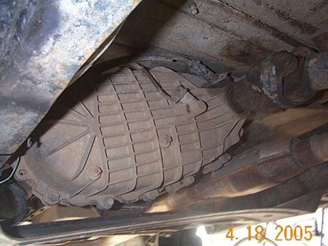 1986 Ford Bronco - A close-up shot reveals the underside of a vehicle's drivetrain, showing a textured transmission casing and driveshaft.
