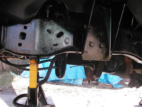 1994 Ford Bronco - Close-up view of a vehicle's undercarriage, focusing on the frame and suspension system supported by jack stands.