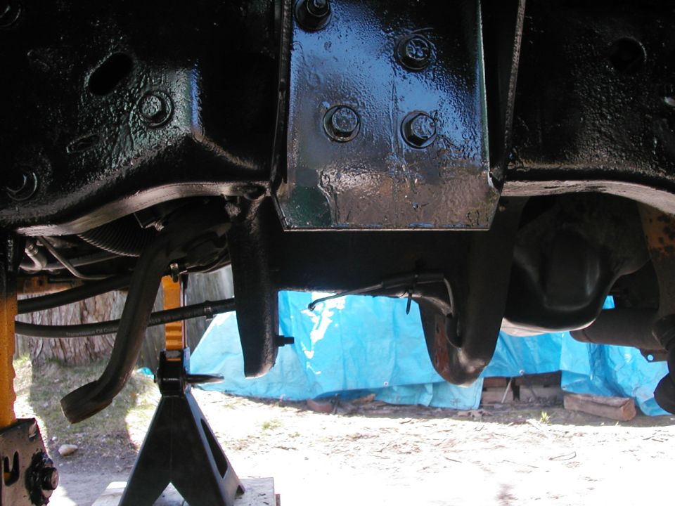 Underside of a lifted truck frame and crossmember on a jack stand