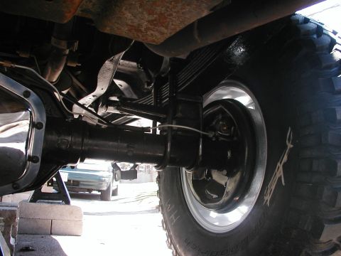 1994 Ford Bronco - Close-up of the rear suspension and axle assembly, with another vehicle partially visible in the distance.