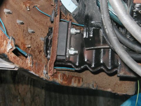 1994 Ford Bronco - This is a close-up view of a vehicle's engine mount and some wiring, showing significant rust on the surrounding metal components.
