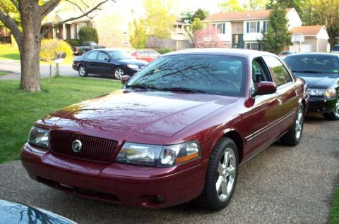 1998 Ford Crown Victoria - Maroon Mercury Marauder parked on a driveway with a black car behind it.