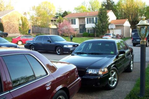 1998 Ford Crown Victoria - Multiple sedans are parked in a residential driveway.