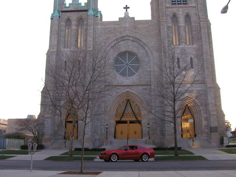 2005 Ford Mustang - A red 2005 Ford Mustang is parked in front of a large stone church.