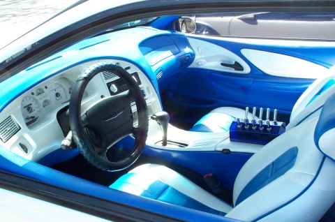 1998 Ford Crown Victoria - Custom two-tone blue and white car interior viewed through the driver's window, showing a black leather-wrapped steering wheel with a Ford…