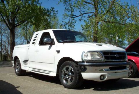 1998 Ford Crown Victoria - A white Ford F-150 extended-cab pickup shown from a front three-quarter angle, with chrome five-spoke wheels, side body-panel vents, a chro…