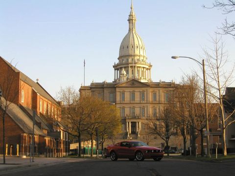 2005 Ford Mustang - A red 2005 Ford Mustang is parked on a street with the Michigan State Capitol building in the background.