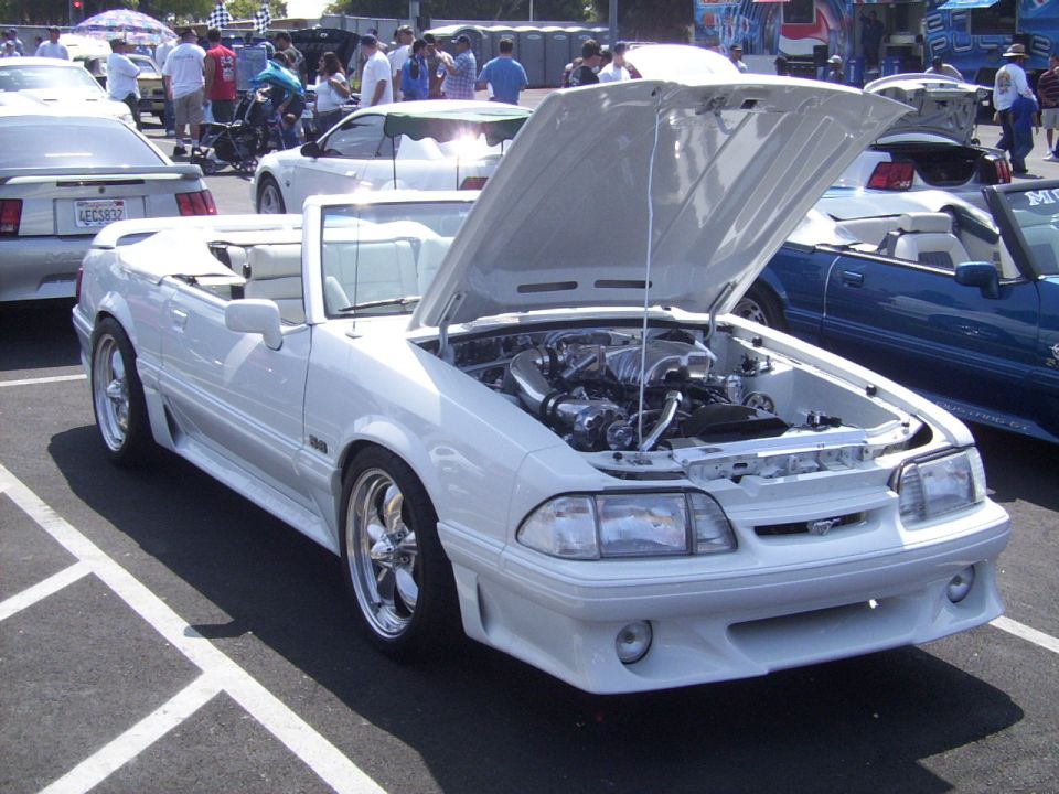 White convertible with hood open, showing engine. Chrome wheels and custom body kit