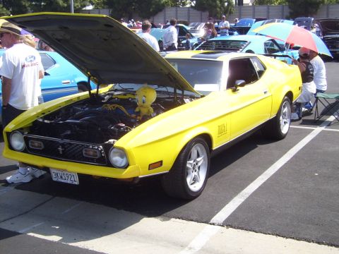 2002 Ford Mustang - A yellow 1971 Ford Mustang Mach 1 is displayed with its hood open, revealing a Tweety Bird toy in the engine bay.