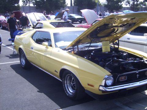 2002 Ford Mustang - A yellow 1971 Ford Mustang is displayed with its hood open at a car show, alongside other vehicles.