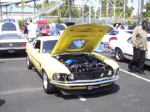 2002 Ford Mustang - Yellow 1969 Ford Mustang Boss 302 on display with hood open, parked outdoors.