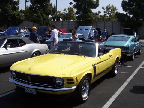 2002 Ford Mustang - A yellow 1970 Ford Mustang convertible is parked at an outdoor car show with other classic vehicles.