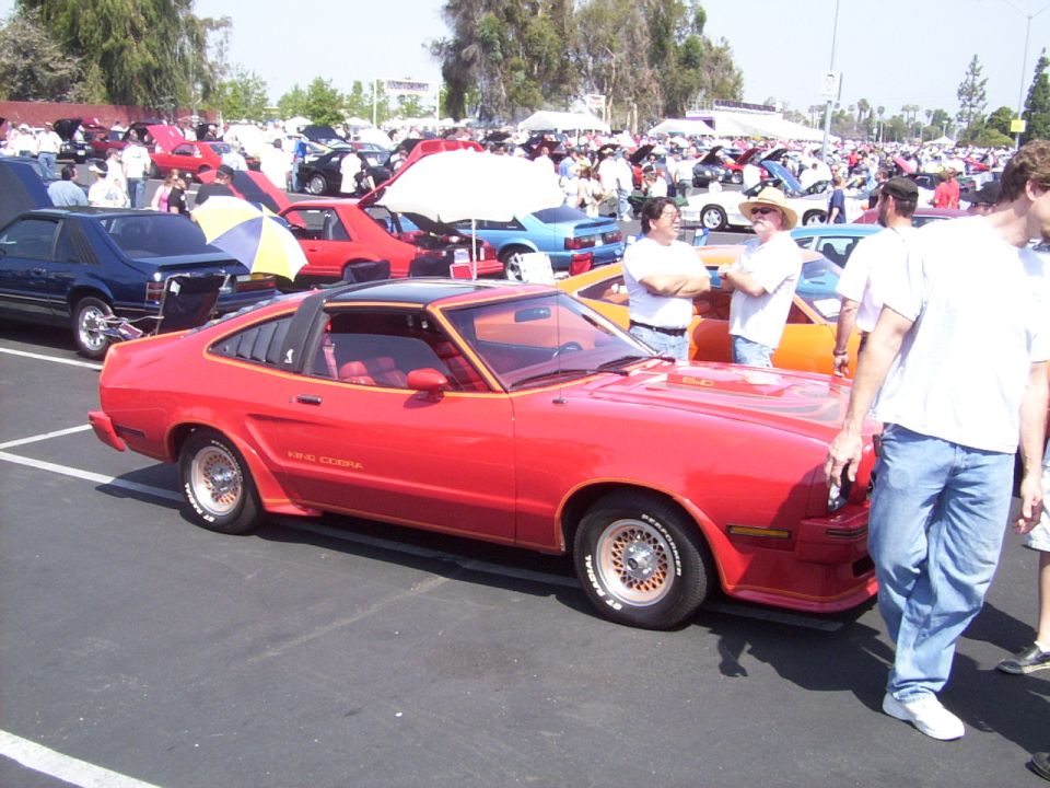Red 1978 Ford Mustang King Cobra coupe with louvers and black t-top at a car show