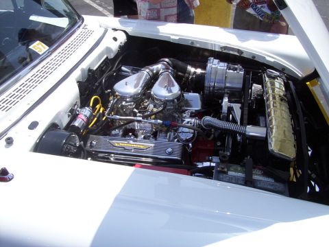 2002 Ford Mustang - The engine bay of a classic car is shown, a powerful V8 engine with dual carburetors and chrome accents.