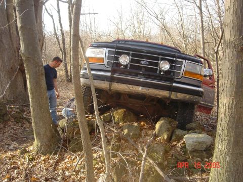 1995 Ford Bronco - Ford Bronco navigating rocky off-road terrain with assistance from two individuals.