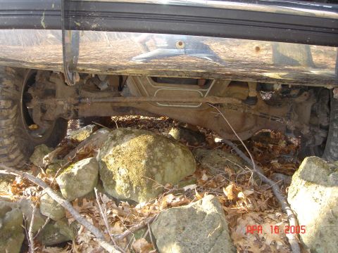 1995 Ford Bronco - The underside of a vehicle is shown navigating a rocky, wooded area.