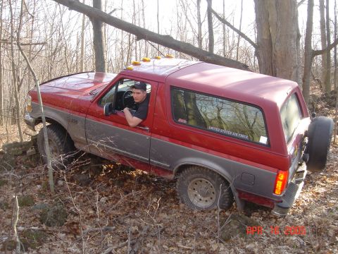 1995 Ford Bronco - 1995 Ford Bronco navigating rough terrain in a wooded area.