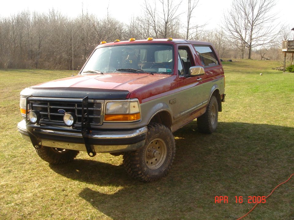 Red and silver 1995 Ford Bronco parked on grass