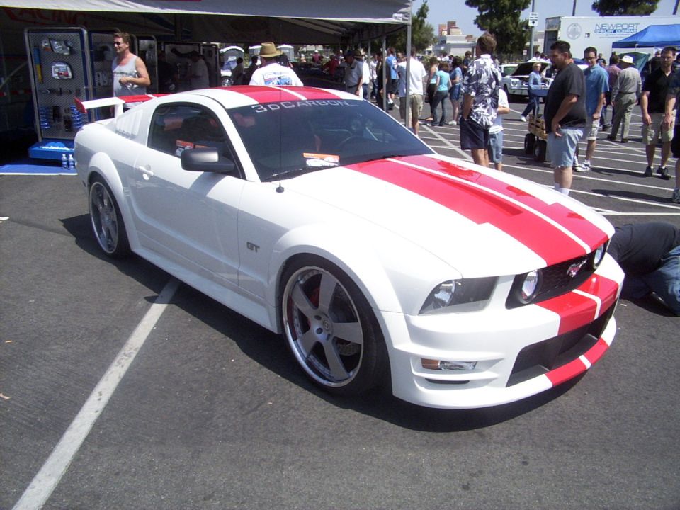 White Ford Mustang GT with red stripes on hood and roof. Custom body kit and wheels