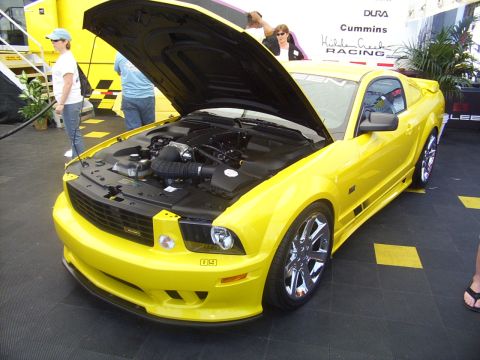 2002 Ford Mustang - A bright yellow Ford Mustang is displayed with its hood up, revealing the engine bay.