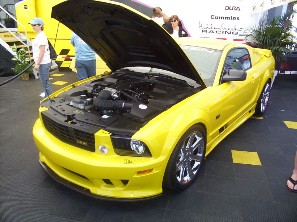 Yellow 2005 Ford Mustang coupe with hood open, showing engine and chrome wheels