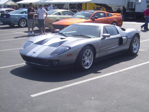 2002 Ford Mustang - A silver Ford GT is parked in a lot, with other vehicles and people in the background.