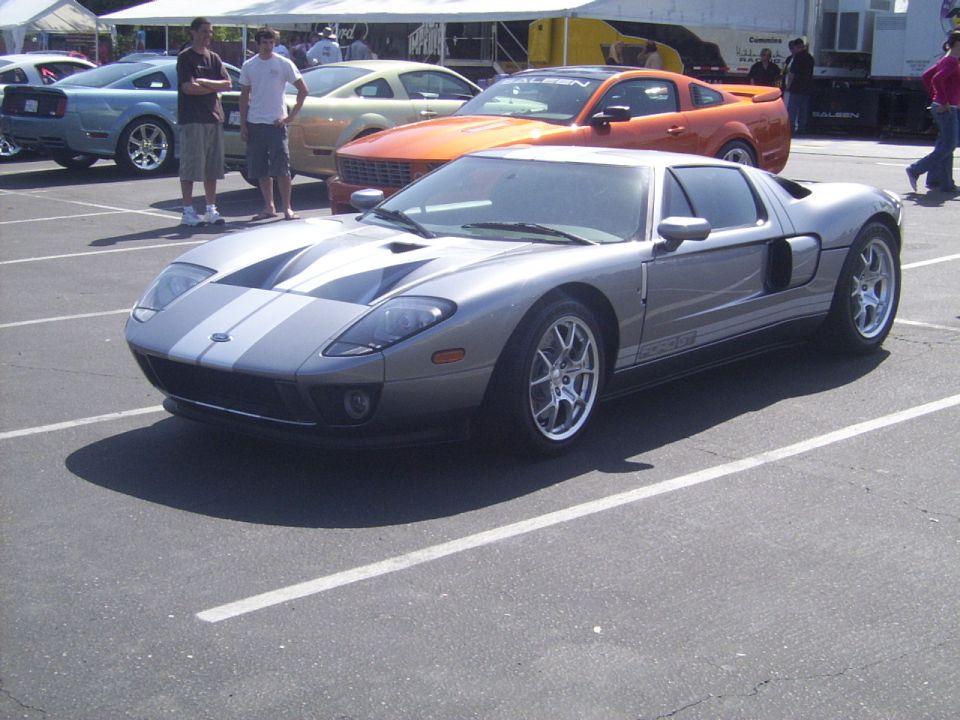 Silver Ford GT with dual gray racing stripes, parked in a lot