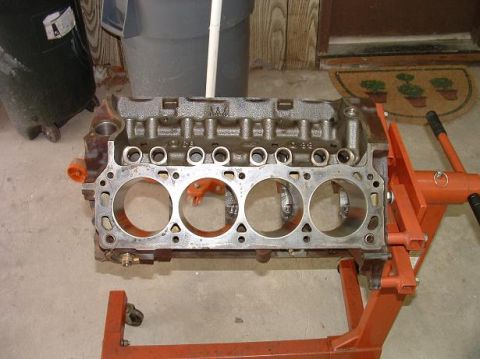 1985 Ford LTD Crown Victoria - An engine block is mounted on an orange stand, ready for assembly or inspection.