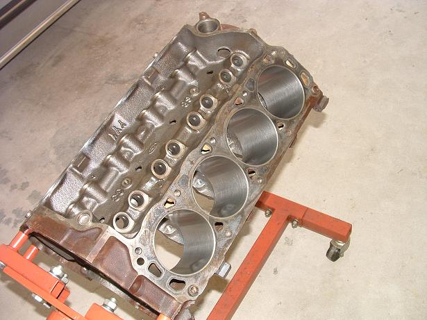Cast iron engine block with cylinder bores, mounted on an orange engine stand