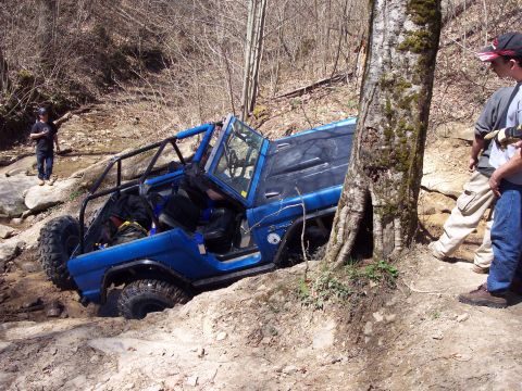 1974 Ford Bronco - Off-road adventure park photo shows a blue 1974 Ford Bronco stuck on a dirt and rock trail.