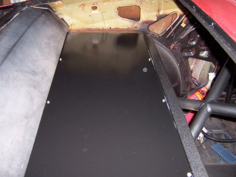 1971 Ford Mustang - The interior of a vehicle shows a custom black panel installed in the rear, with a roll cage structure.