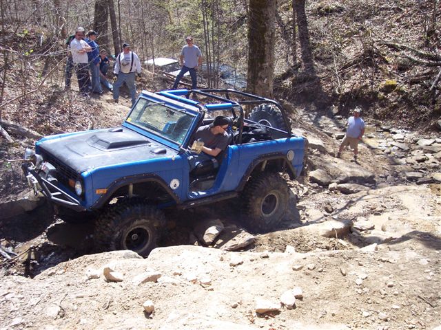 Blue 1974 Ford Bronco off-roading on a rocky trail