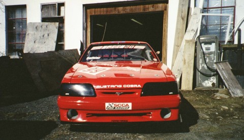 1993 Ford Mustang - Front view of a red 1993 Ford Mustang Cobra R race car, showing its distinctive grille and headlights.