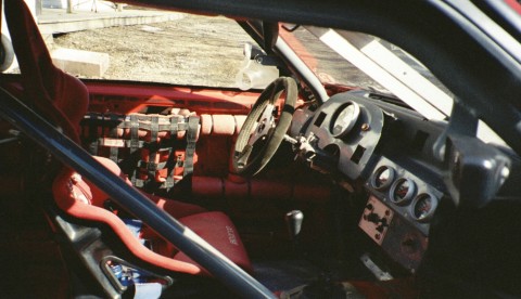 1993 Ford Mustang - The interior of a race car shows a roll cage, racing seat, and dashboard with gauges.