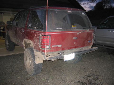 1991 Ford Explorer - Rear view of a red 1991 Ford Explorer, showing its lifted suspension and off-road tires.