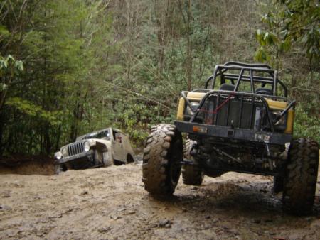 1989 Ford Bronco - Off-road vehicles navigate a muddy trail, with one vehicle deeply stuck.