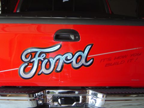 1978 Ford Bronco - The tailgate of a red Ford pickup truck displays custom lettering and a slogan.