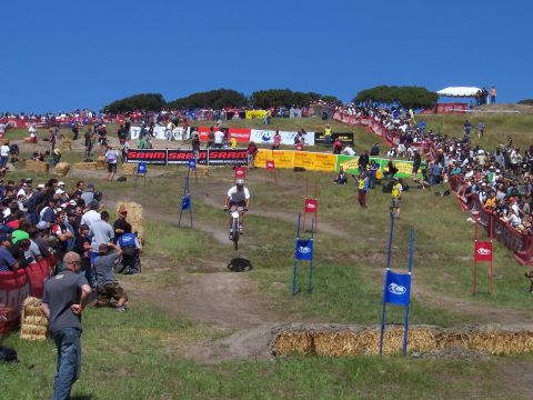1998 Ford Ranger - A mountain bike race is underway with a rider on the track and crowds watching from the hillsides.
