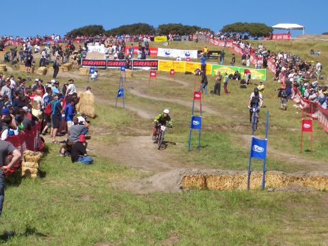 1998 Ford Ranger - Spectators gather to watch a downhill mountain bike race event with various sponsor banners visible.