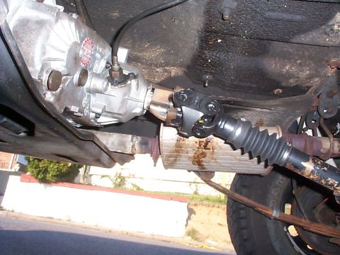 1989 Jeep YJ - The underside of a vehicle reveals the transmission and driveshaft, with a red sticker visible on the transmission housing.