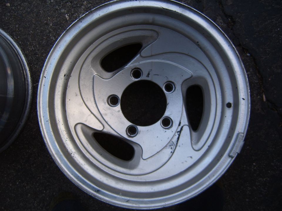 Silver alloy wheel with five lug holes and a swirling spoke design