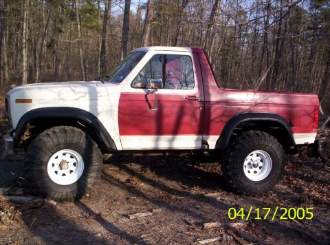 1985 Ford Bronco - This 1985 Ford Bronco features a distinctive two-tone red and white paint scheme and is equipped with large off-road tires.