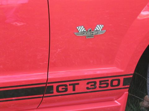 2005 Ford Mustang - Close-up of a red Ford Mustang's side, showing the GT 350 stripe and a 46HP badge.