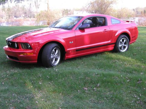 2005 Ford Mustang - This red 2005 Ford Mustang GT 350 is shown from a three-quarter front view, parked on a grassy lawn.