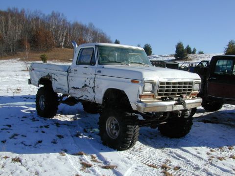 1979 Ford F-150 - This heavily modified pickup truck features oversized tires and a prominent exhaust pipe, seen in a snowy outdoor setting.