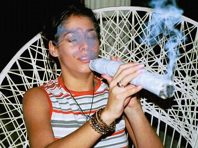 Woman smoking a large joint, smoke obscuring face