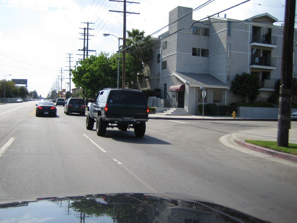 Black lifted SUV driving down a residential street viewed from behind